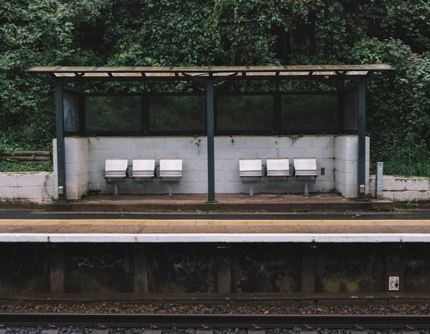 Interior view of an empty train carriage at Barnes Bridge Station, featuring rows of upholstered seats with multicolored patterned fabric on both sides. The carriage has a clean, well-maintained appea